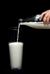 person pouring milk in highball glass